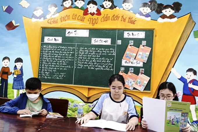 Các học sinh đọc truyện tuyên truyền bảo vệ môi trường tại thư viện trường