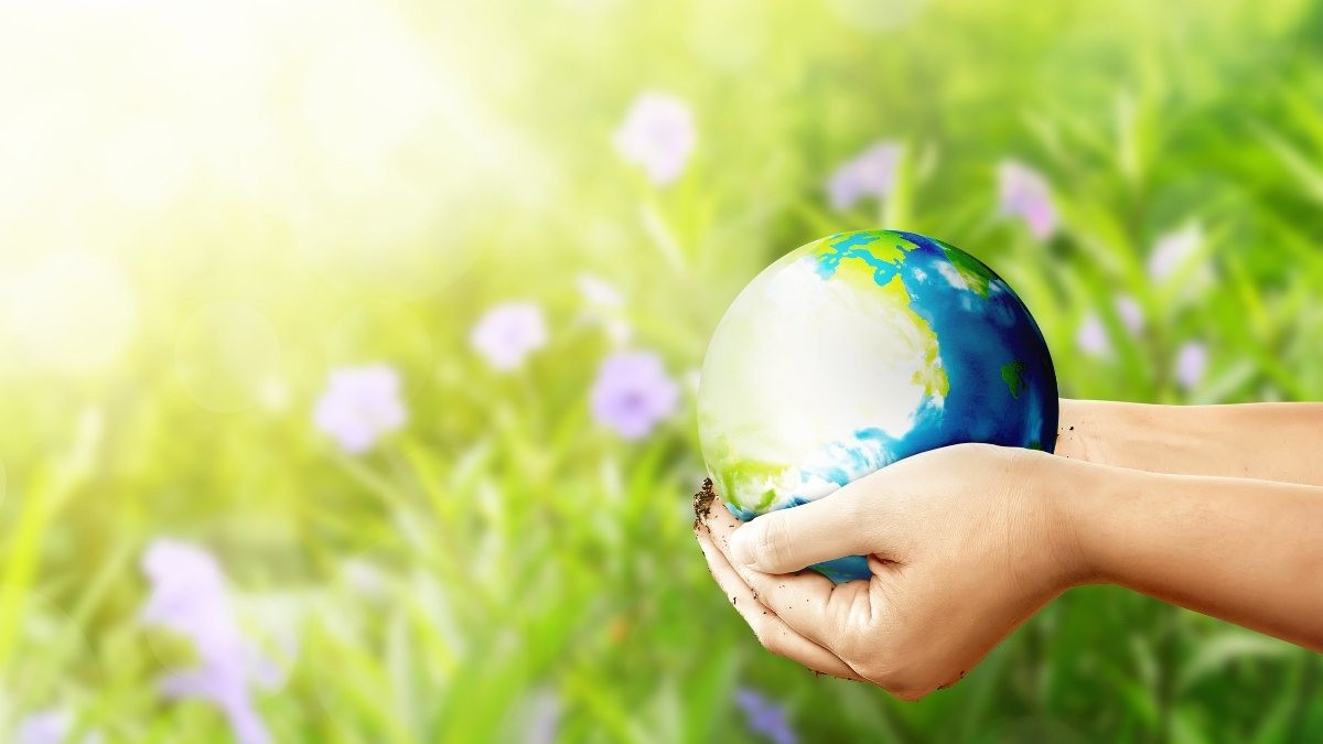 Hình ảnh quả địa cầu đang được ôm bởi bàn tay con người, tượng trưng cho trách nhiệm chung đối với nền bảo vệ môi trường toàn cầu.