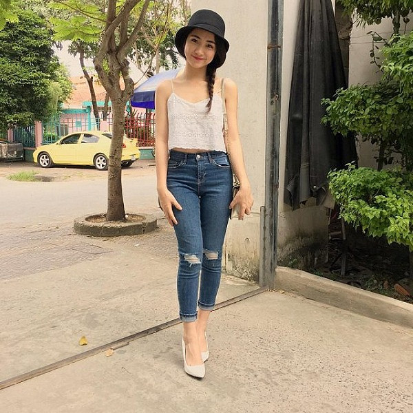 Một cô gái năng động với áo hai dây và quần jeans cạp cao, chiếc quần jeans cũ này là nguồn nguyên liệu hoàn hảo để tái chế thành váy ngắn hoặc váy xòe.