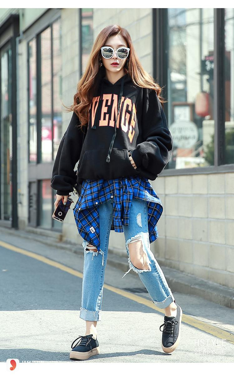 Một cô gái trẻ trung mặc áo hoodie và quần jeans rách, chiếc quần jeans này đại diện cho vật liệu lý tưởng để tái chế quần jeans thành váy phong cách cá tính.
